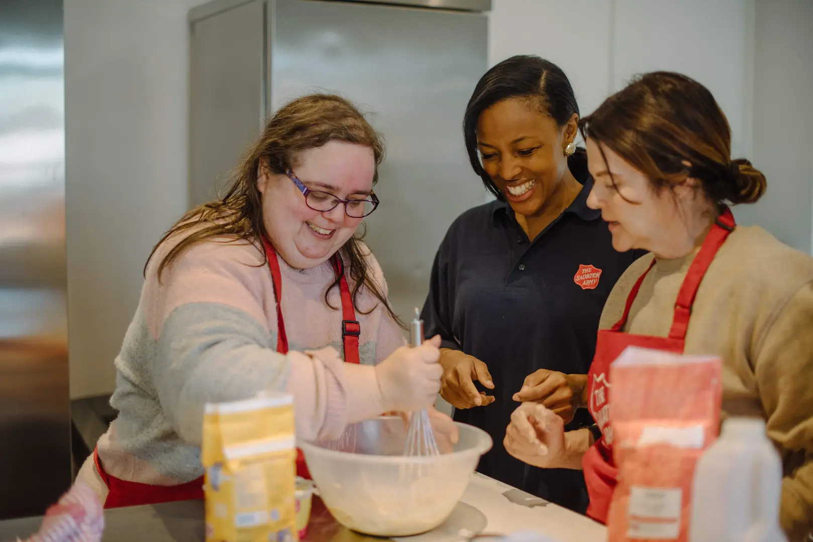 Three women attending a cooking class, looking happy and like they are enjoying the experience.