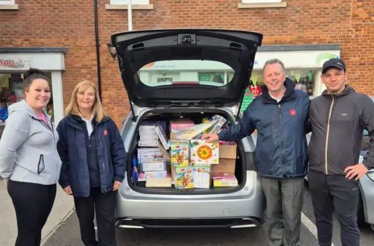 People stood by a car full of presents