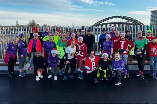A group of festively dressed runners pose on a bridge