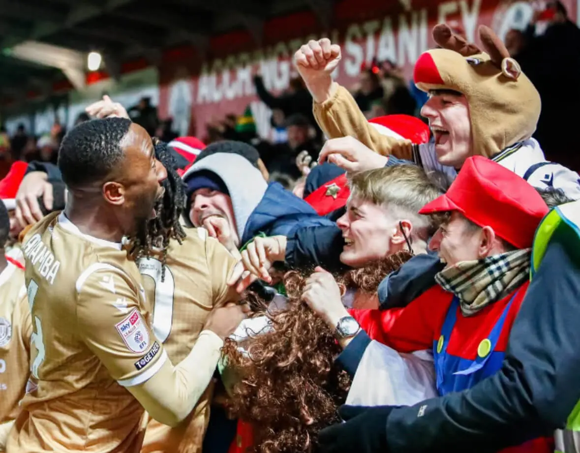 Bromley FC fans celebrate with a player after the team scored.