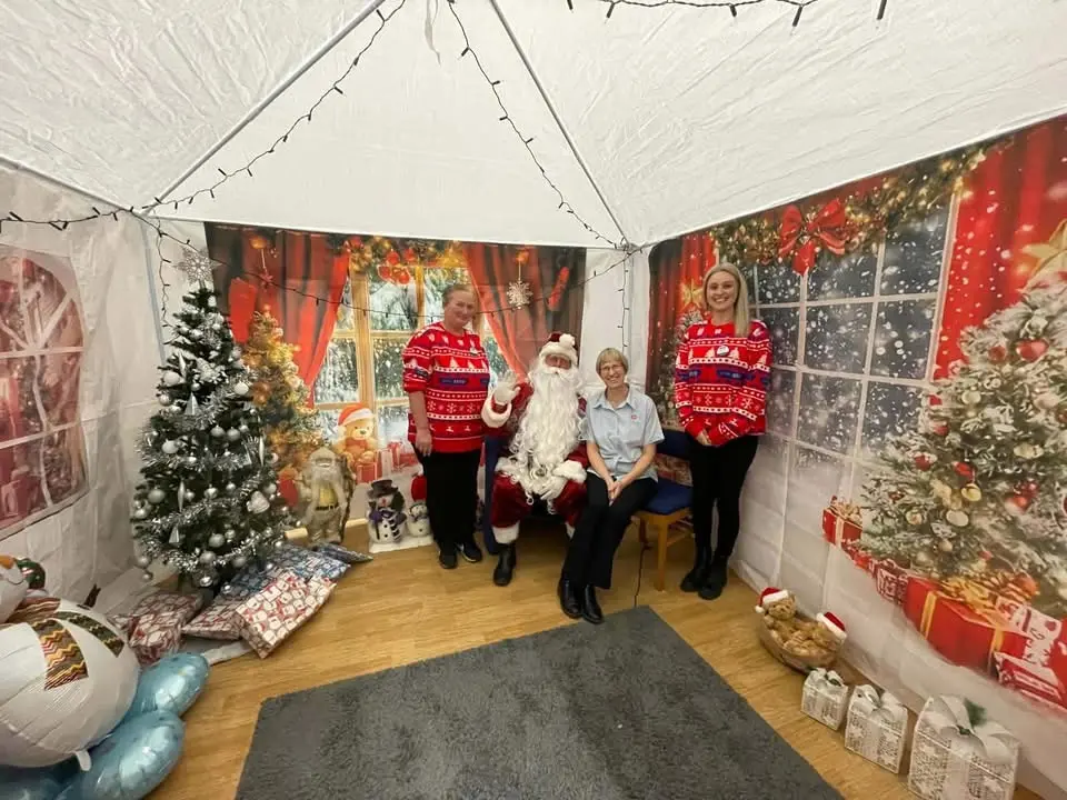 Inside Santa's Grotto at Hove Corps with Father Christmas, Corps Lead and 2 organisers from One Stop convenience storee