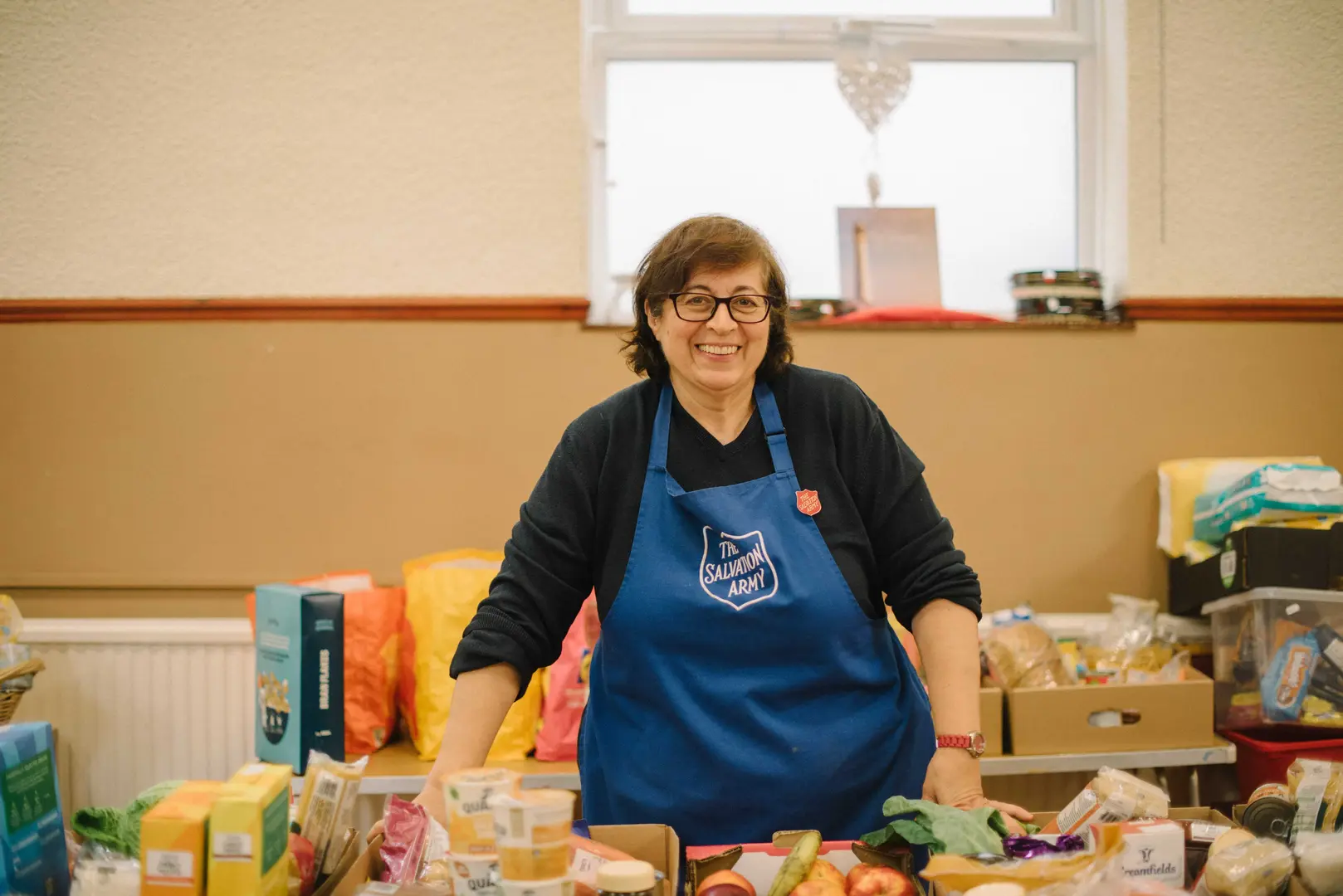 A woman wearing a Salvation Army tabard, working at a food kitchen.