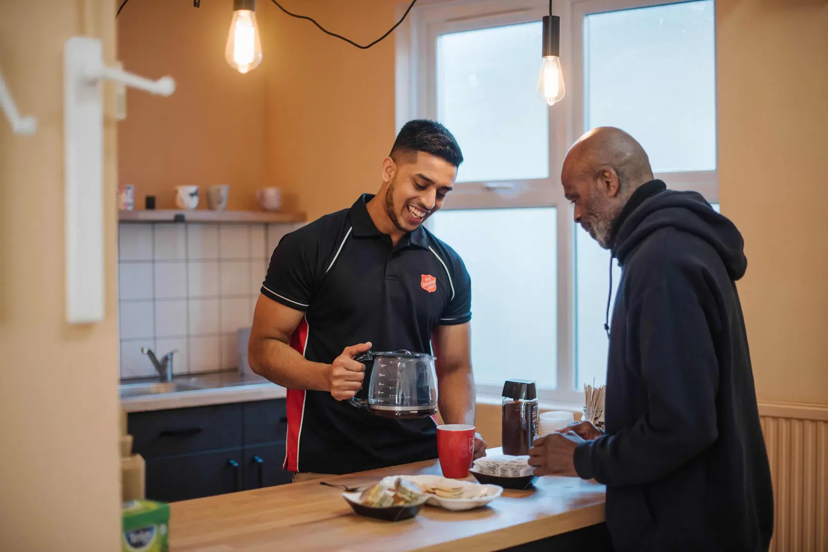 A member of staff pouring a man a cup of tea.