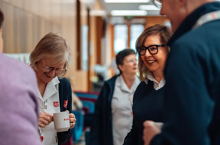 Salvation Army officers and staff laughing together in William Booth College's hub.