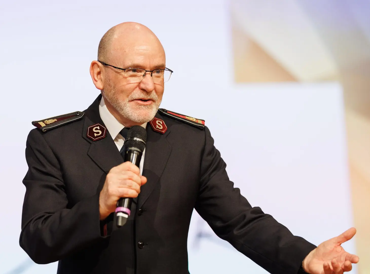 General Lyndon Buckingham, world leader of The Salvation Army, in uniform, speaking with microphone.