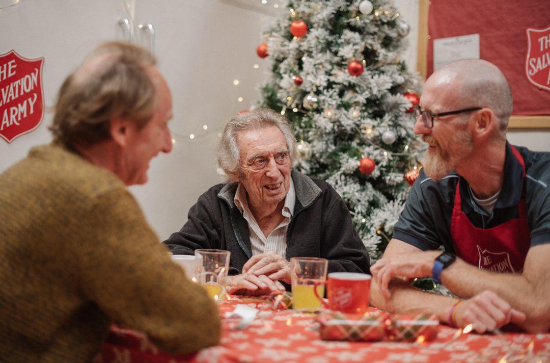 A photo of an older man having a Christmas lunch with a Salvation Army volunteer
